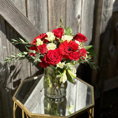 Red and white roses with a red gerbera daisy in a glass vase