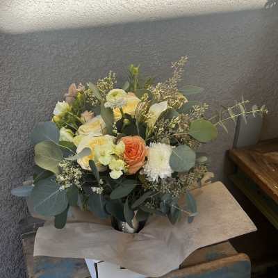 Mixed bouquet of pale roses and white blooms in a metal vase