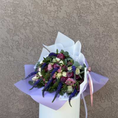 Bouquet of pink, white, and purple roses wrapped in lavender paper