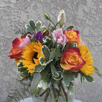 Sunflowers and roses arranged in a glass vase