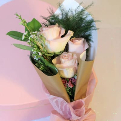 Bouquet of pale pink roses wrapped in gold paper with a pink ribbon