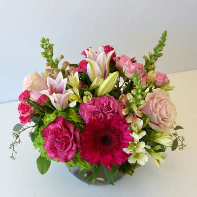 Pink and white mixed flower arrangement in a glass bowl vase