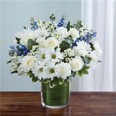 White and blue mixed flower arrangement in a glass vase