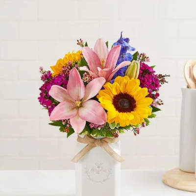 Bouquet of pink lilies and yellow sunflowers in a white vase