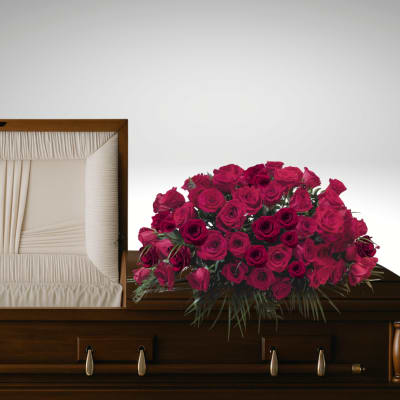 Casket spray of deep pink roses on a wooden casket
