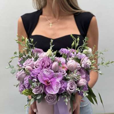Lavender bouquet with roses, carnations, and an orchid in a pink hat box