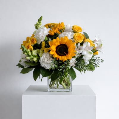 Yellow sunflower bouquet with white and yellow flowers in a clear glass vase