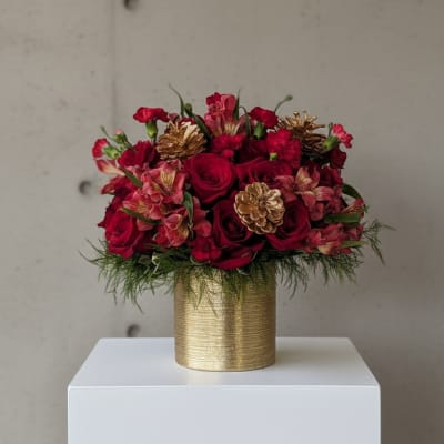 Red rose bouquet in a gold vase with pinecone accents