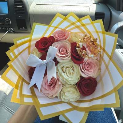 Bouquet of red, pink, and cream roses wrapped in white and gold paper