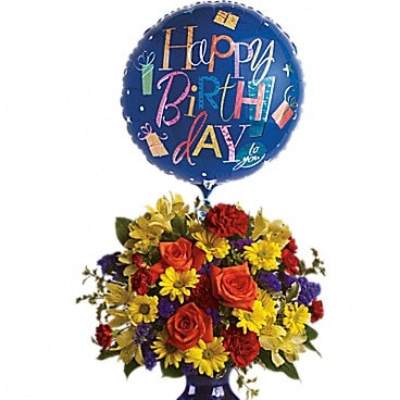 Birthday balloon above a colorful flower arrangement in a blue vase