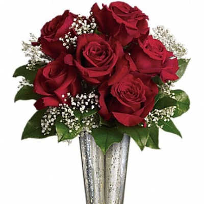 Red roses arranged in a silver vase with baby's breath