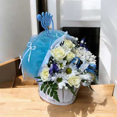 White roses and daisies in a white basket with a blue mesh wrap