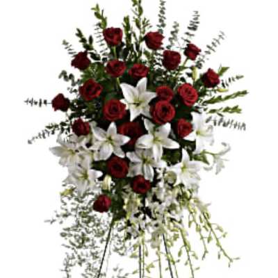 Standing floral spray with red roses and white lilies on a metal easel