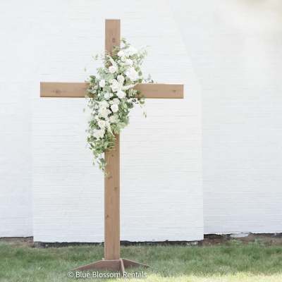 White floral arrangement on a wooden cross stand
