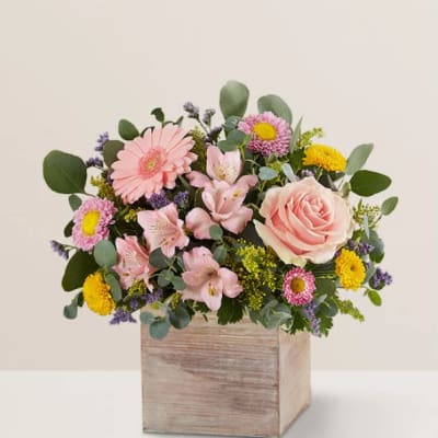 Pink and yellow mixed flower arrangement in a wooden box