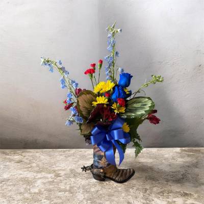 Mixed bouquet in a cowboy boot vase with a blue ribbon
