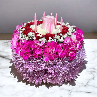 Round floral centerpiece with a pink rose and pink candles