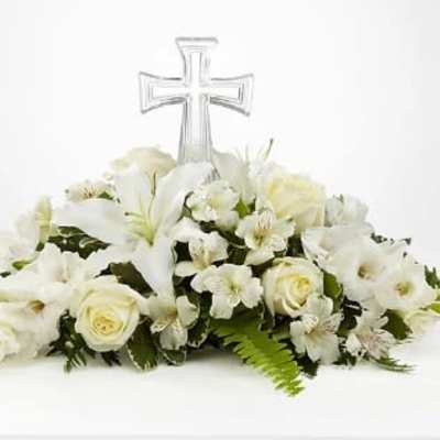 White floral casket spray with a clear cross topper