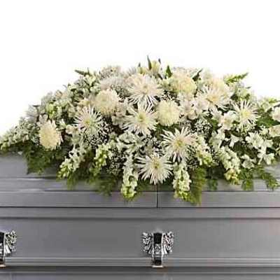 White floral casket spray on a gray casket