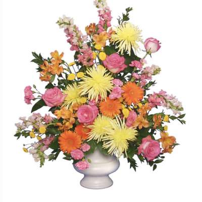 Mixed bouquet of pink roses, orange daisies, and yellow spider mums in a white vase