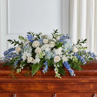 White and blue floral arrangement on a wooden casket
