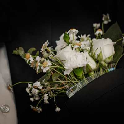 White boutonniere with small daisies and roses on a black suit jacket
