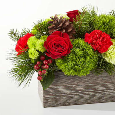 Red roses and carnations in a rectangular wooden box with pinecones