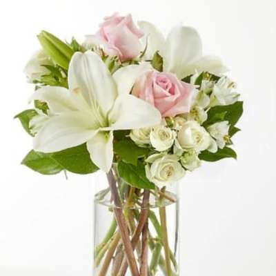 Clear glass vase with white lilies and pale pink and white roses.