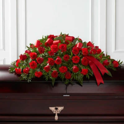 Red rose and carnation casket spray with a red ribbon