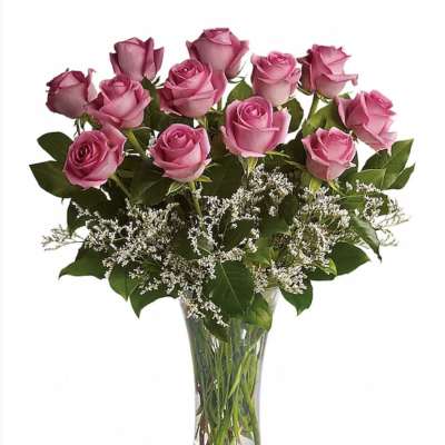 Tall clear vase of pink roses with white filler flowers