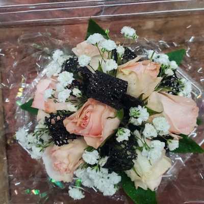 Small bouquet of pale pink roses with white filler flowers in clear wrap