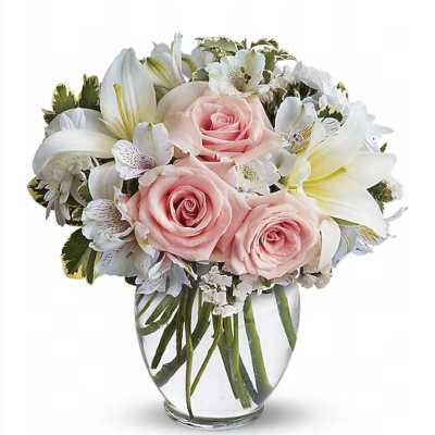 Compact arrangement of pink roses and white lilies in a clear glass vase