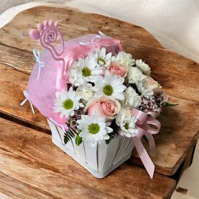 Pink and white flower arrangement in a white basket with ribbon