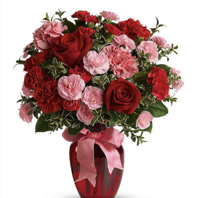 Red roses and pink carnations in a red vase with a pink ribbon