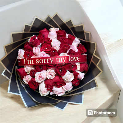 Bouquet of red and pale pink roses with a ribbon reading "I'm sorry my love"
