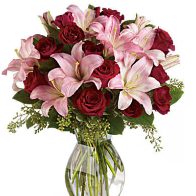 Bouquet of pink lilies and red roses in a clear glass vase
