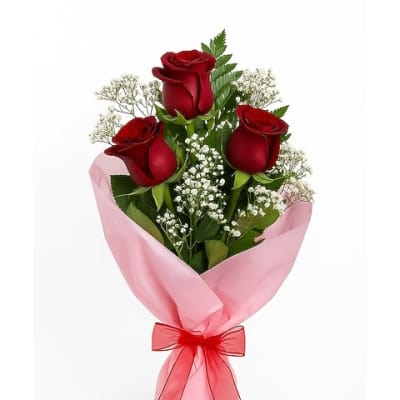 Bouquet of red roses wrapped in pink paper with a red ribbon
