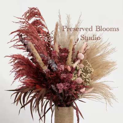Tall dried arrangement of red and natural pampas in a twine-wrapped cylinder vase