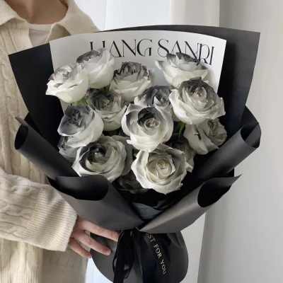 Bouquet of white roses wrapped in black paper