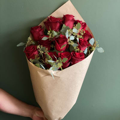 Hand-tied bouquet of red roses wrapped in brown paper