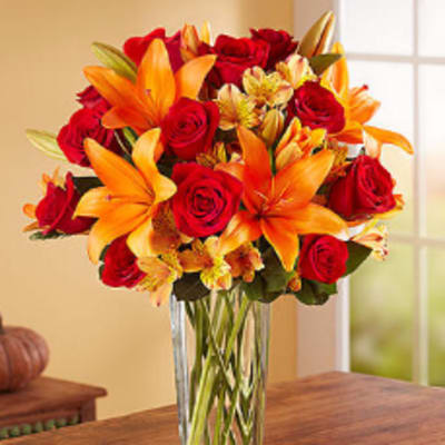 Bouquet of red roses and orange lilies in a clear glass vase