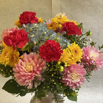 Bouquet of pink, yellow, and blue flowers in a clear glass vase
