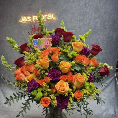 Large mixed bouquet of roses, carnations, and greenery in a glass vase