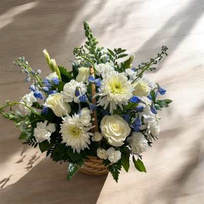 White and blue floral arrangement in a wicker basket