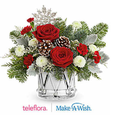 Red roses and white flowers in a clear glass vase with pinecones