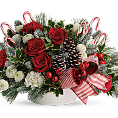 Christmas arrangement with red roses, candy canes, and pinecones in a white container
