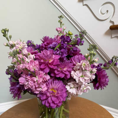 Pink and purple mixed flowers arranged in a clear glass vase