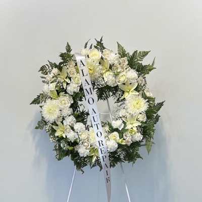 White funeral wreath on a stand with roses and lilies