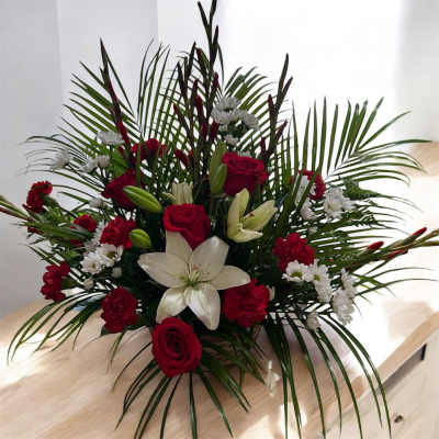 Red roses and white lilies arranged with white daisies in a low bouquet