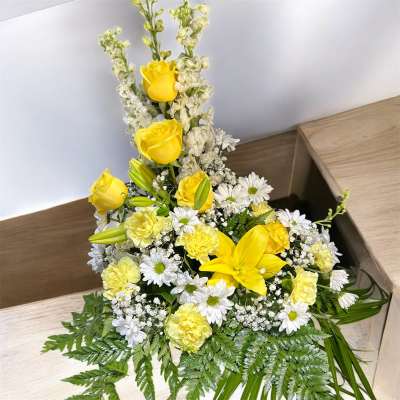 Yellow roses and lilies with white daisies in a low floral arrangement